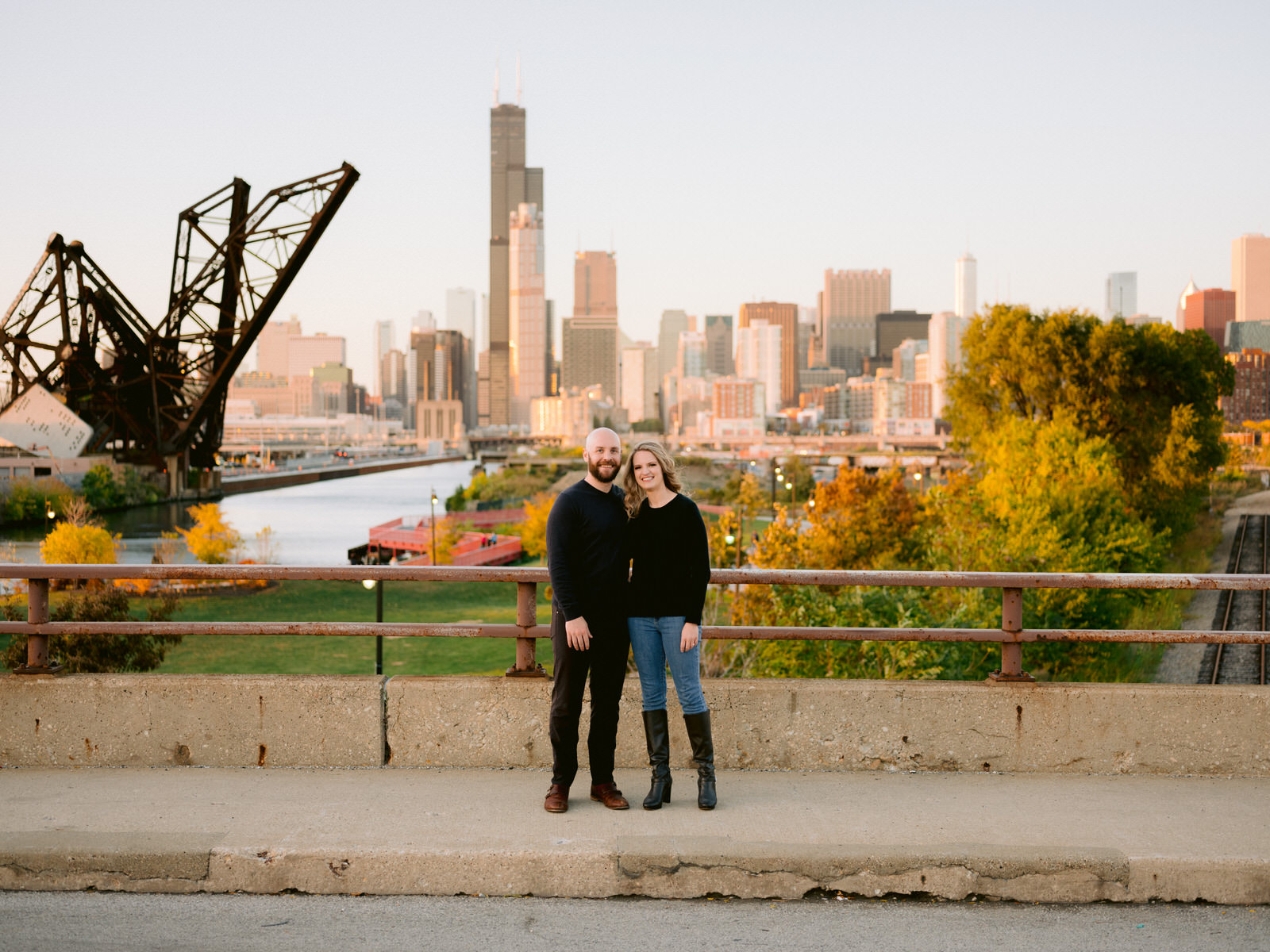 ping tom memorial park engagement photos couple facing camera and smiling in front of Chicago skyline and river