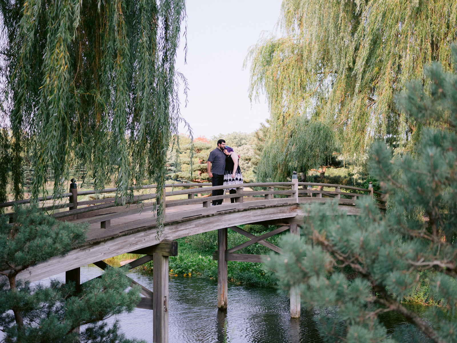 Couple stands on a bridge at Chicago Botanic Gardens for Chicago engagement session locations. Wedding photography by Michael & Kristin Photo and Video