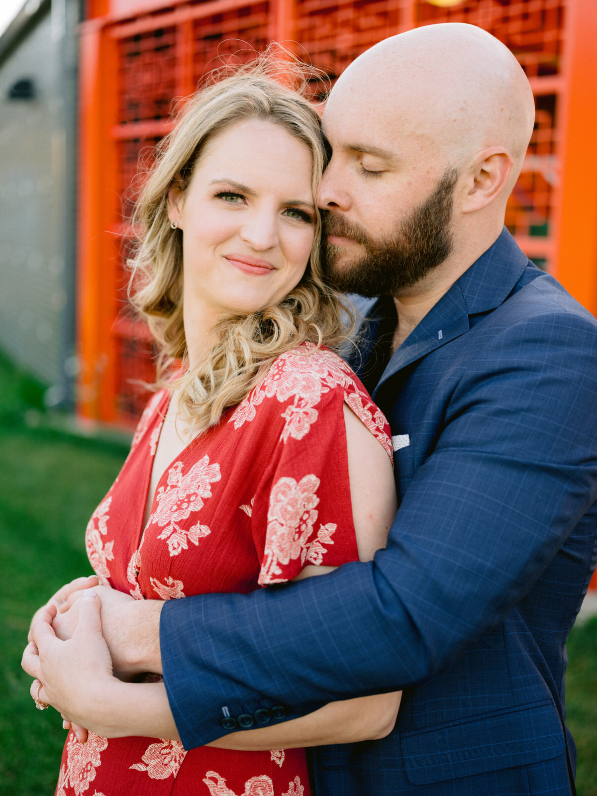 Couple cuddles in front of orange structure at Ping Tom Memorial Park for Chicago engagement session locations. Wedding photography by Michael & Kristin Photo and Video