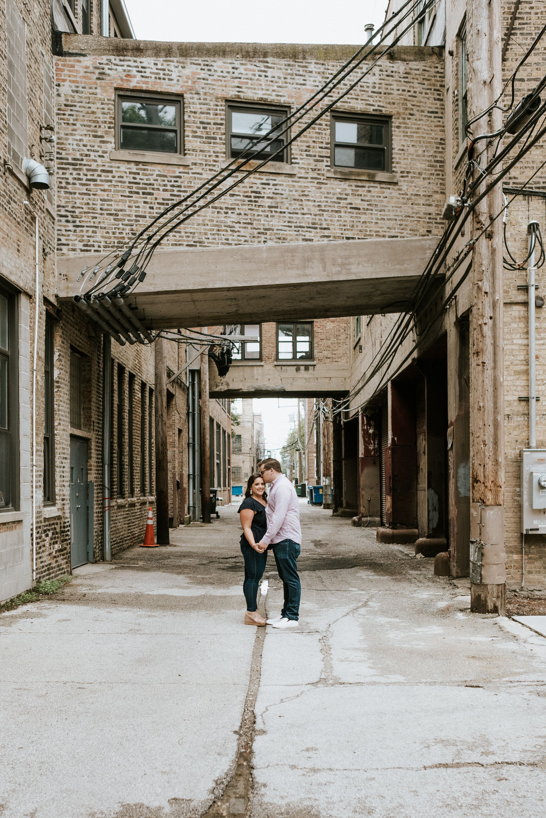 Couple standing underneath a brick building breezeway connecting two Chicago buildings for Chicago engagement session locations. Photography by Michael & Kristin Photo and Video