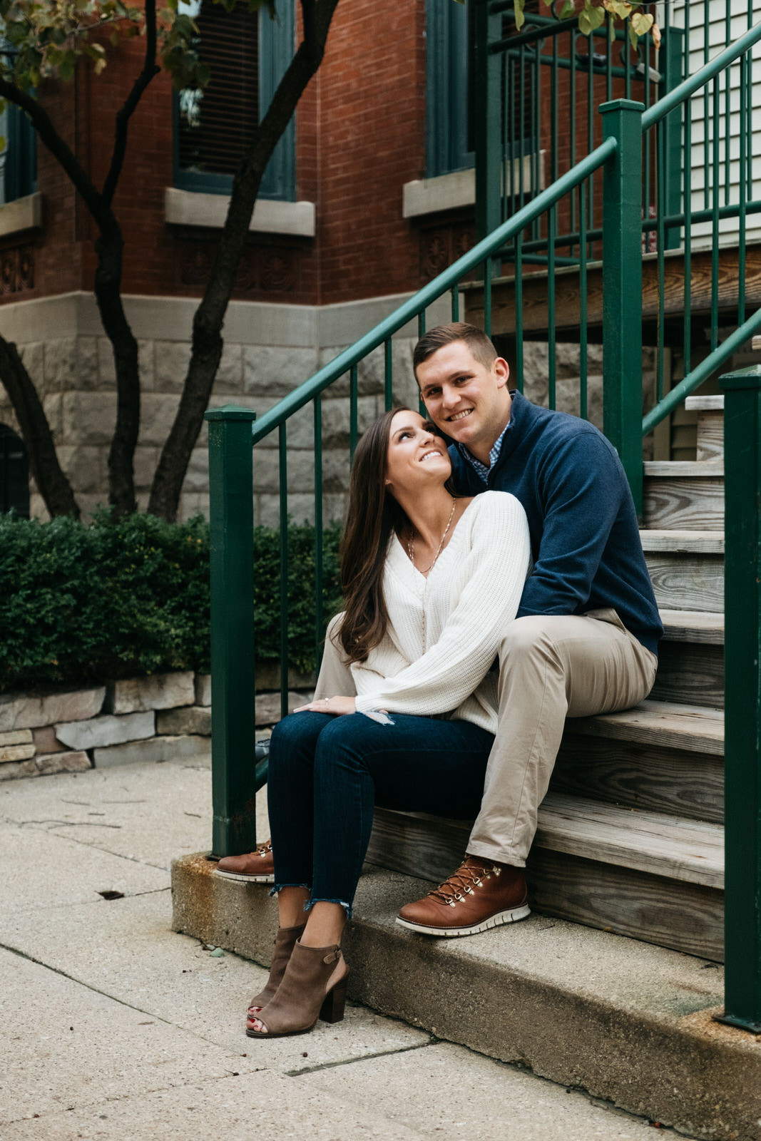 Couple sitting on steps of a greystone building in Chicago for Chicago engagement session locations. Photography by Michael & Kristin Photo and Video