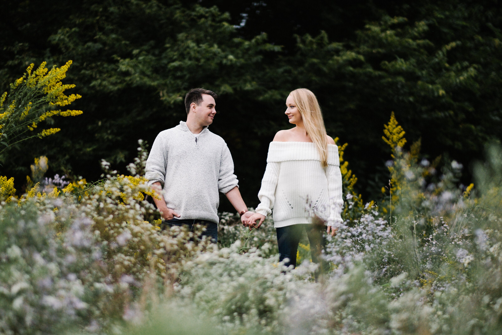 Couple standing amongst wild flowers looking at one another at the Montrose Harbor Bird Sanctuary. Wedding photography by Michael & Kristin Photo and Video