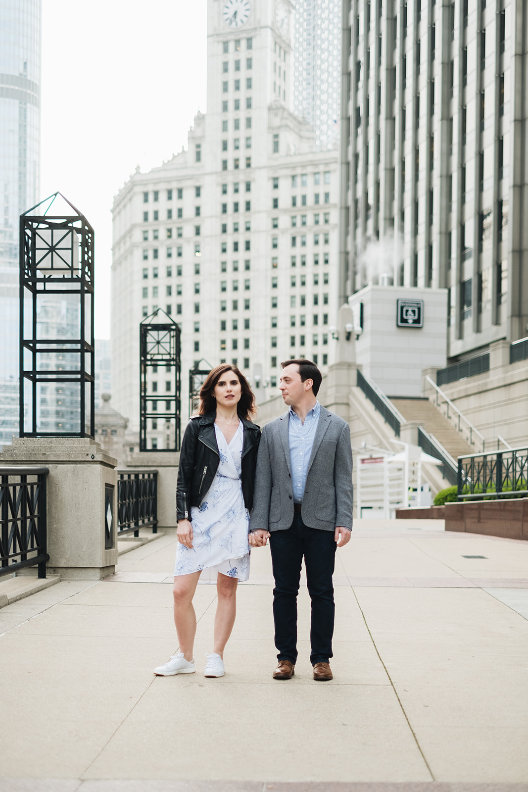 Couple standing in front of buildings for Chicago engagement session locations including The Chicago Riverwalk. Wedding photos by Michael & Kristin Photo and Video