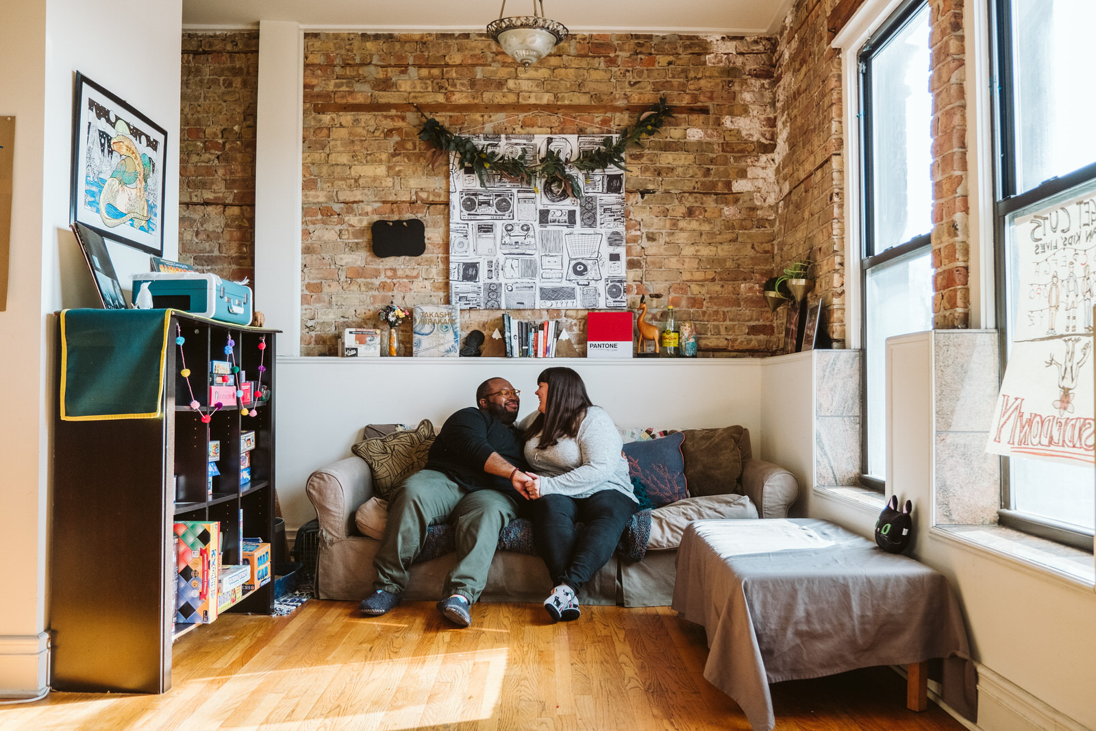 Couple cuddles on the couch in their Pilsen apartment for Chicago engagement session locations. Photography by Michael & Kristin Photo and Video